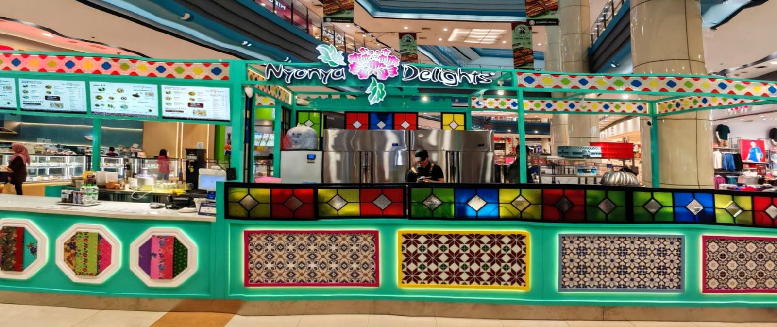 The Nyonya Delights stall — turquoise Peranakan kiosk with colourful stained-glass panels